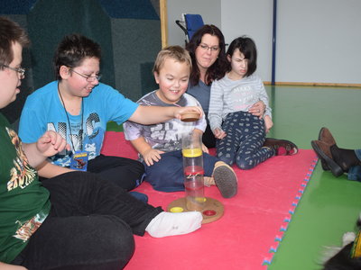 Děti se prostřídají v dávání pamlsku do psího hlavolamu